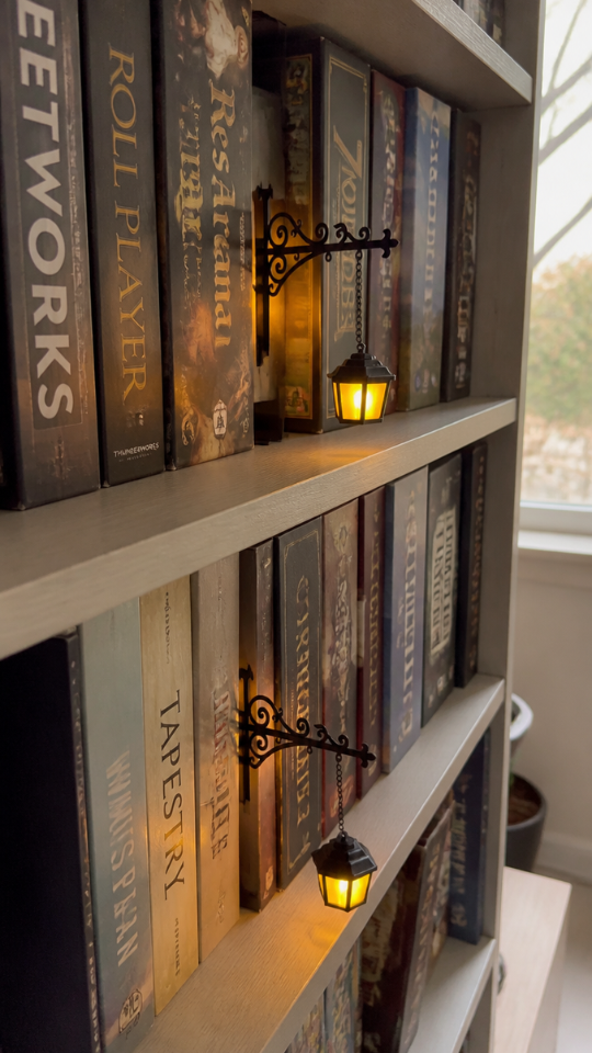 Lanterns lighting a boardgame shelf next to a window