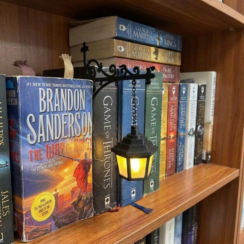 Lantern bookend glowing on a wooden shelf of fantasy paperbacks